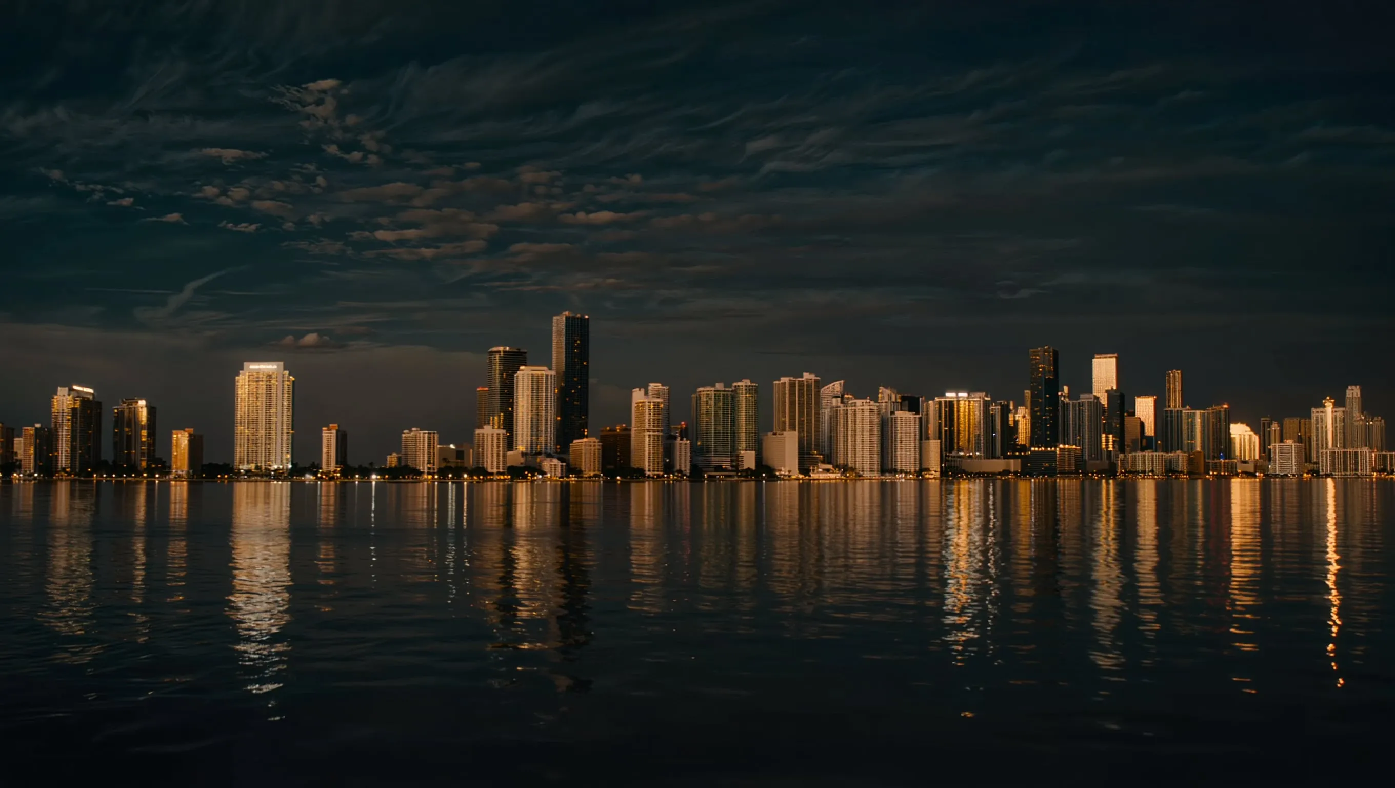 Miami skyline glowing over dark water at night